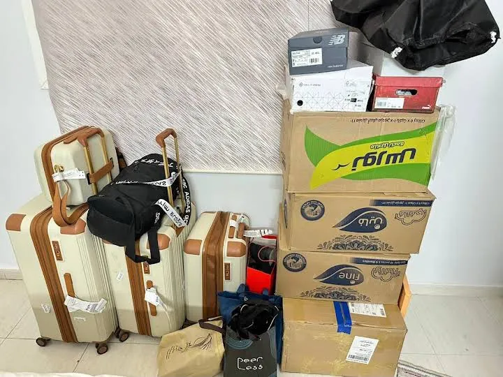 حقائب سفر وكراتين مجمعة في زاوية غرفة بحجم يناسب دباب نقل عفش بالرياض