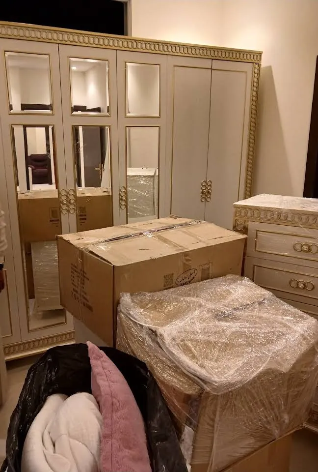 كراتين وقطع أثاث مغلفة أمام دولاب قبل نقل العفش في شرق الرياض
