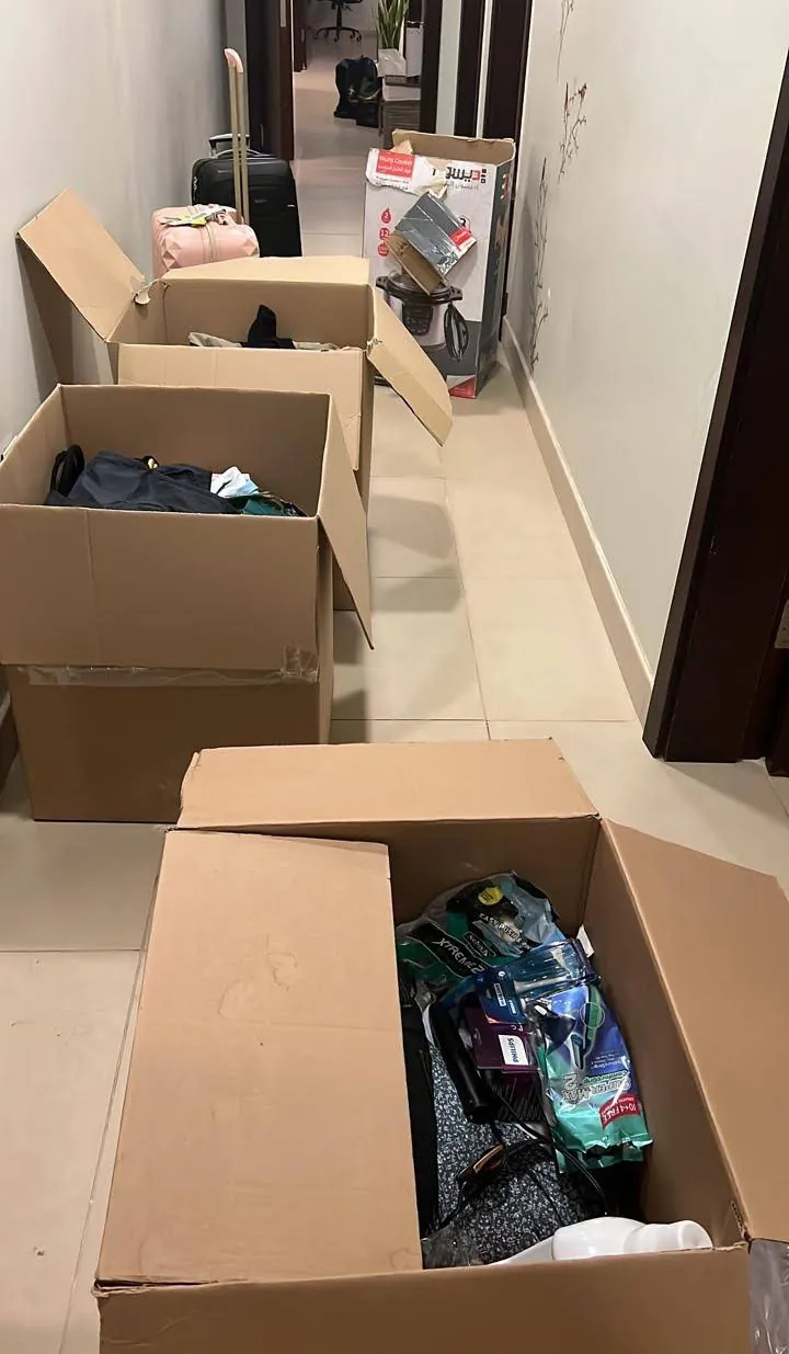 كراتين مفتوحة فيها ملابس وأغراض في ممر شقة